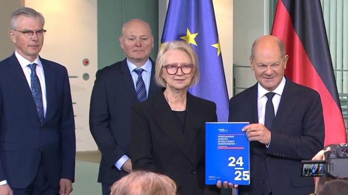 Vorstellung des Jahresgutachtens 24/25. Von links nach rechts: Prof. Martin Werding, Prof. Achim Truger (jeweils Ratsmitglieder), Prof.in Monika Schnitzer (Ratsvorsitzende), Bundeskanzler Olaf Scholz. Screenshot: Fabian Runkel.