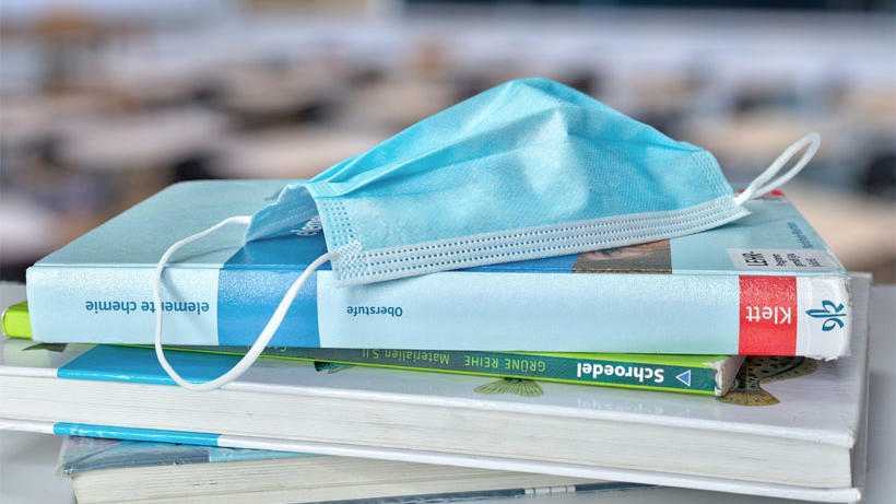 Maske auf einem Bücherstapel Quelle: Pixabay